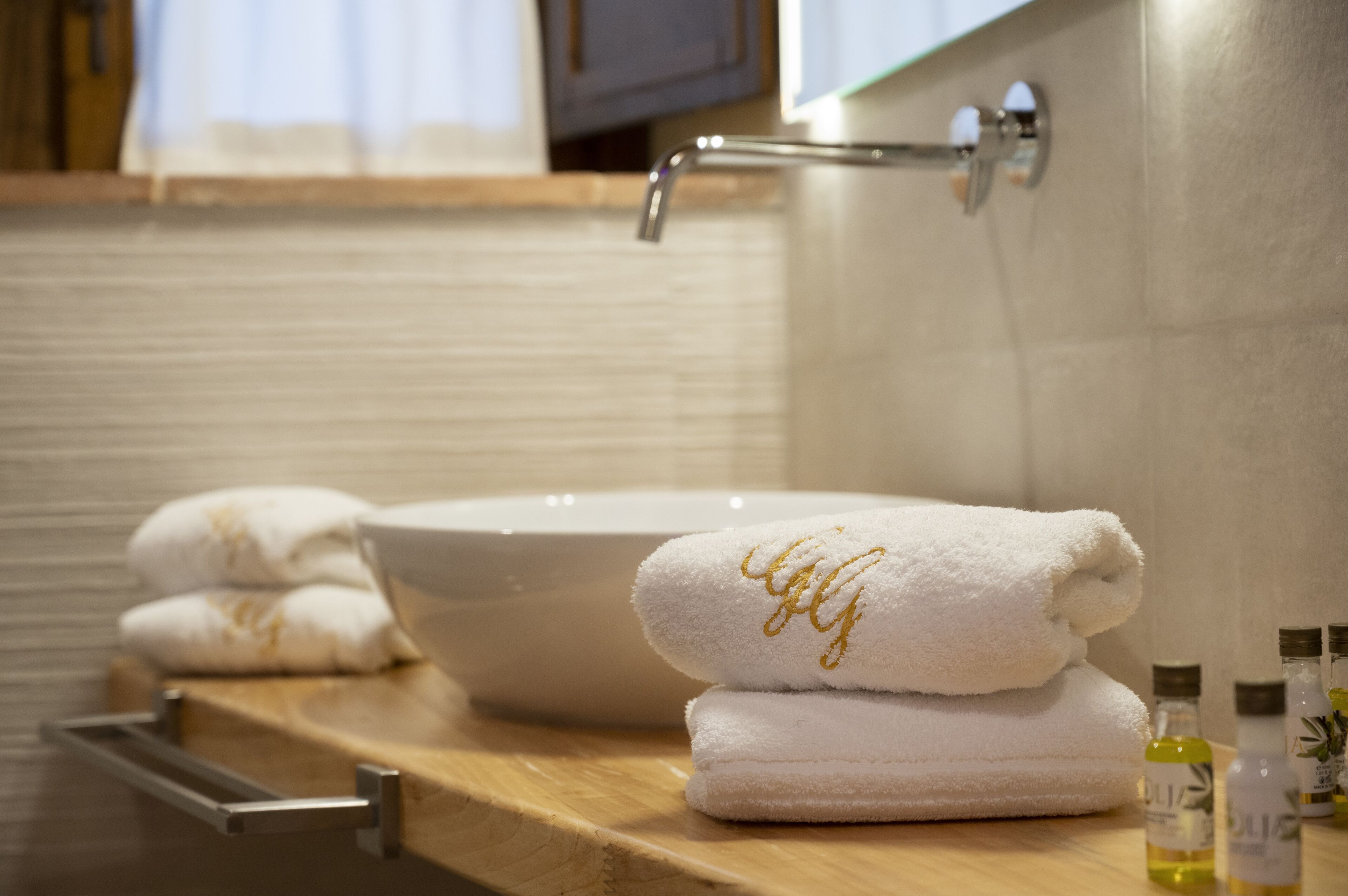 Un baño con un lavamanos grande de color blanco, encimera de madera y toallas dobladas con cuidado.