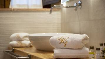 Un baño con un lavamanos grande de color blanco, encimera de madera y toallas dobladas con cuidado.