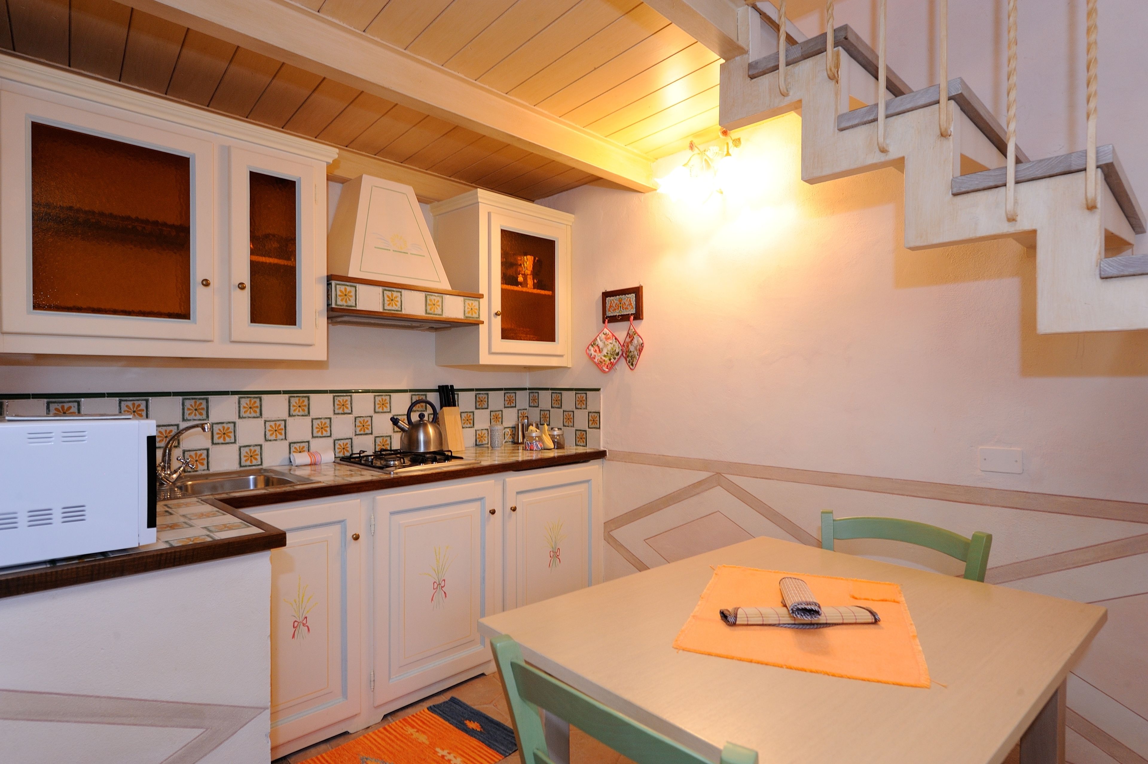 A kitchen with white cabinets, a wooden countertop, and a dining table with chairs.