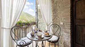 A balcony with a table set for tea, featuring a view of a mountainous landscape. - Torre Del Nera Albergo Diffuso & Spa (Scheggino)