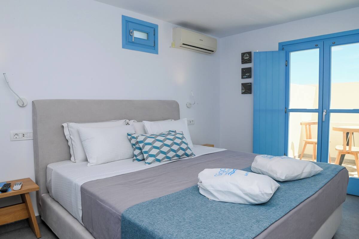 Une chambre d’hôtel équipée d’un lit, d’une table de chevet, d’un climatiseur et offrant une vue sur l’extérieur.