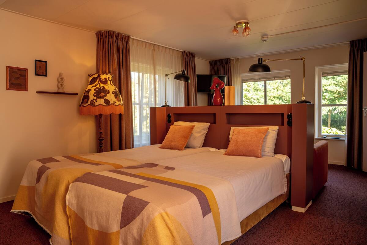 A double bed with a patterned bedspread, a headboard, and two bedside lamps.