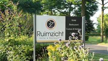 Letrero para el Hotel & Restaurante Ruimzicht, con un logotipo, que enumera servicios como hotel, restaurante y capacitación.