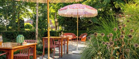Un patio al aire libre con mobiliario de madera, una mesa y dos sombrillas.