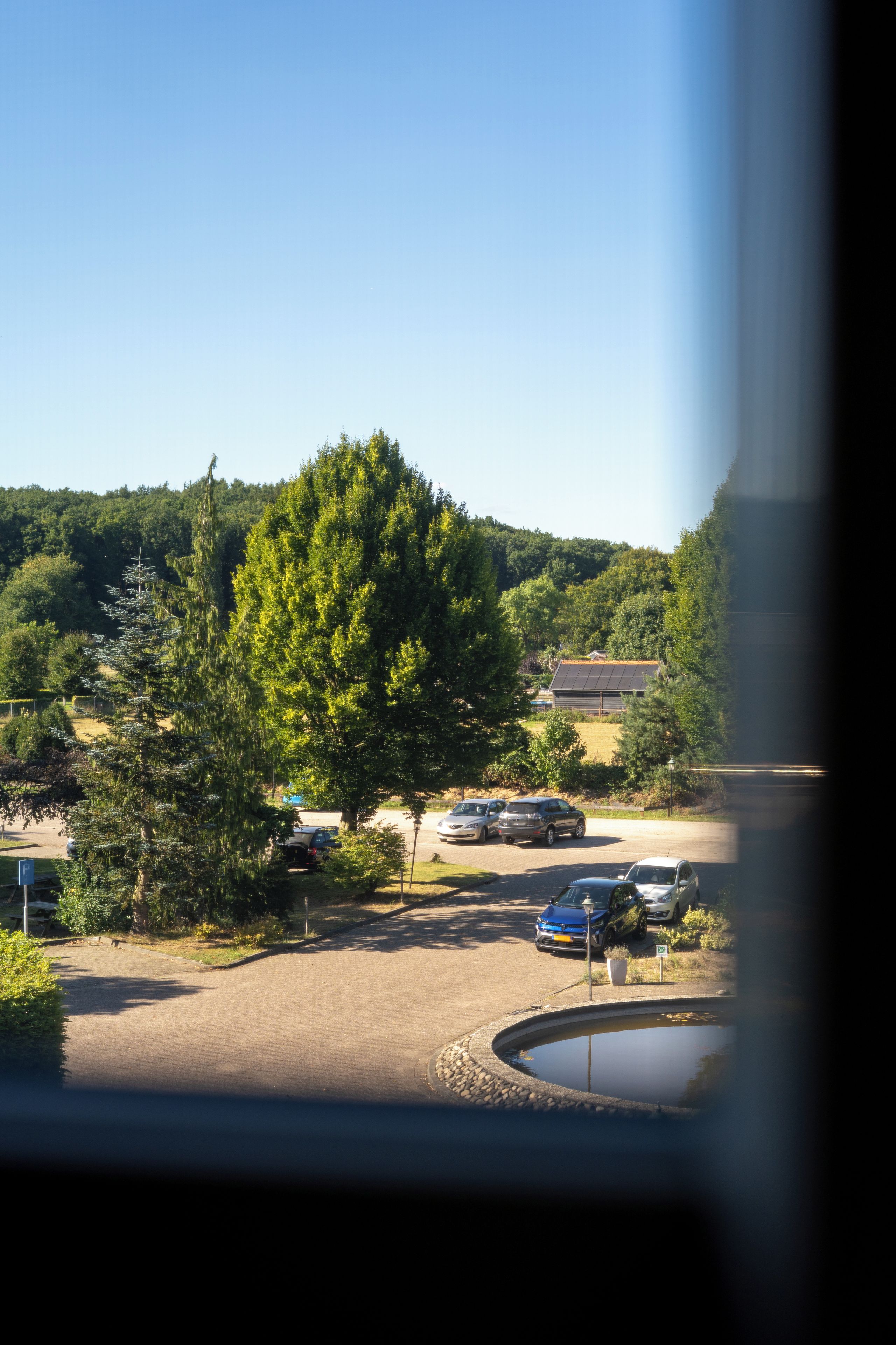 A parking area with cars, a tree, and a building in the background.