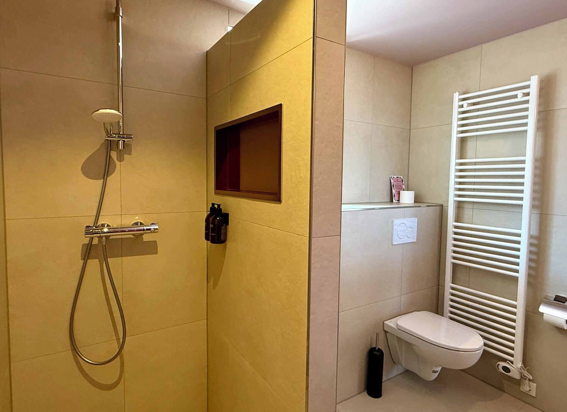 Un baño con ducha, inodoro y perchero para toallas.