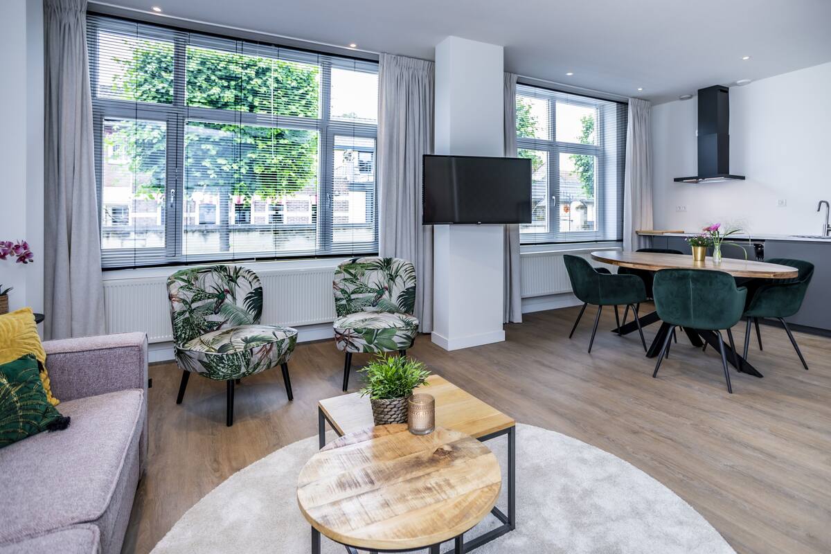 A modern living room with a sofa, chairs, a coffee table, and a dining area with a table and chairs.
