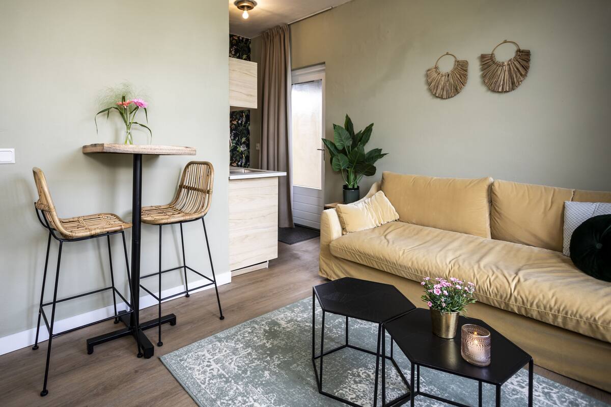A living room with a sofa, two chairs, a coffee table, and a small table with a plant.