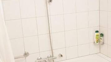 A bathroom with a bathtub, a shower, and a towel rack.
