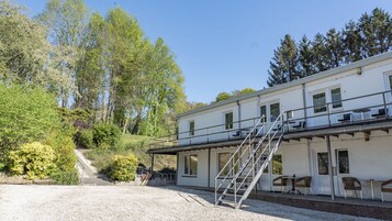 A building with a covered outdoor area, a staircase, and a gravel path leading to it.