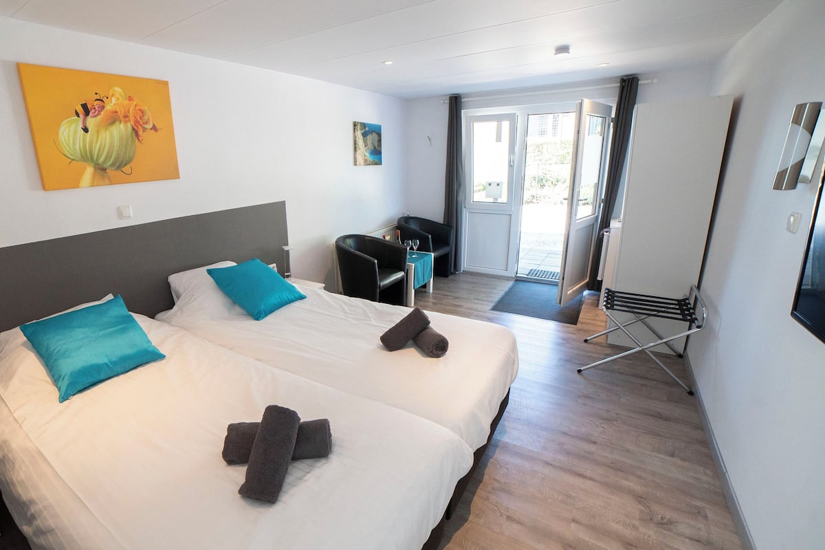 Een hotelkamer met twee bedden, een bureau, een stoel en een eettafel.