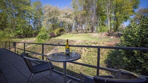 Une terrasse avec une table et des chaises, donnant sur un jardin aménagé avec des arbres et des arbustes.