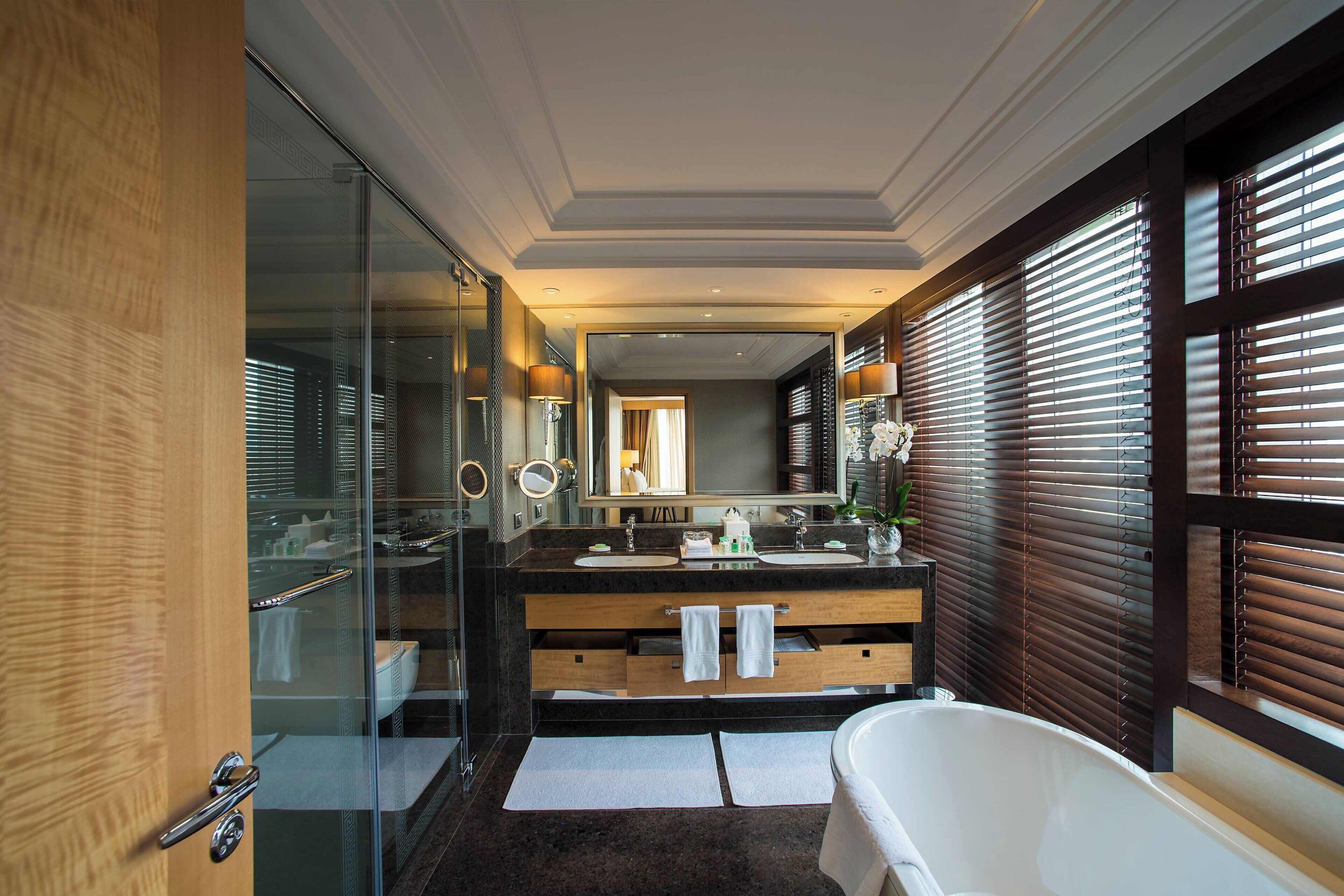 Een moderne badkamer met een douchecabine van glas, twee wasbakken en een vrijstaand bad.