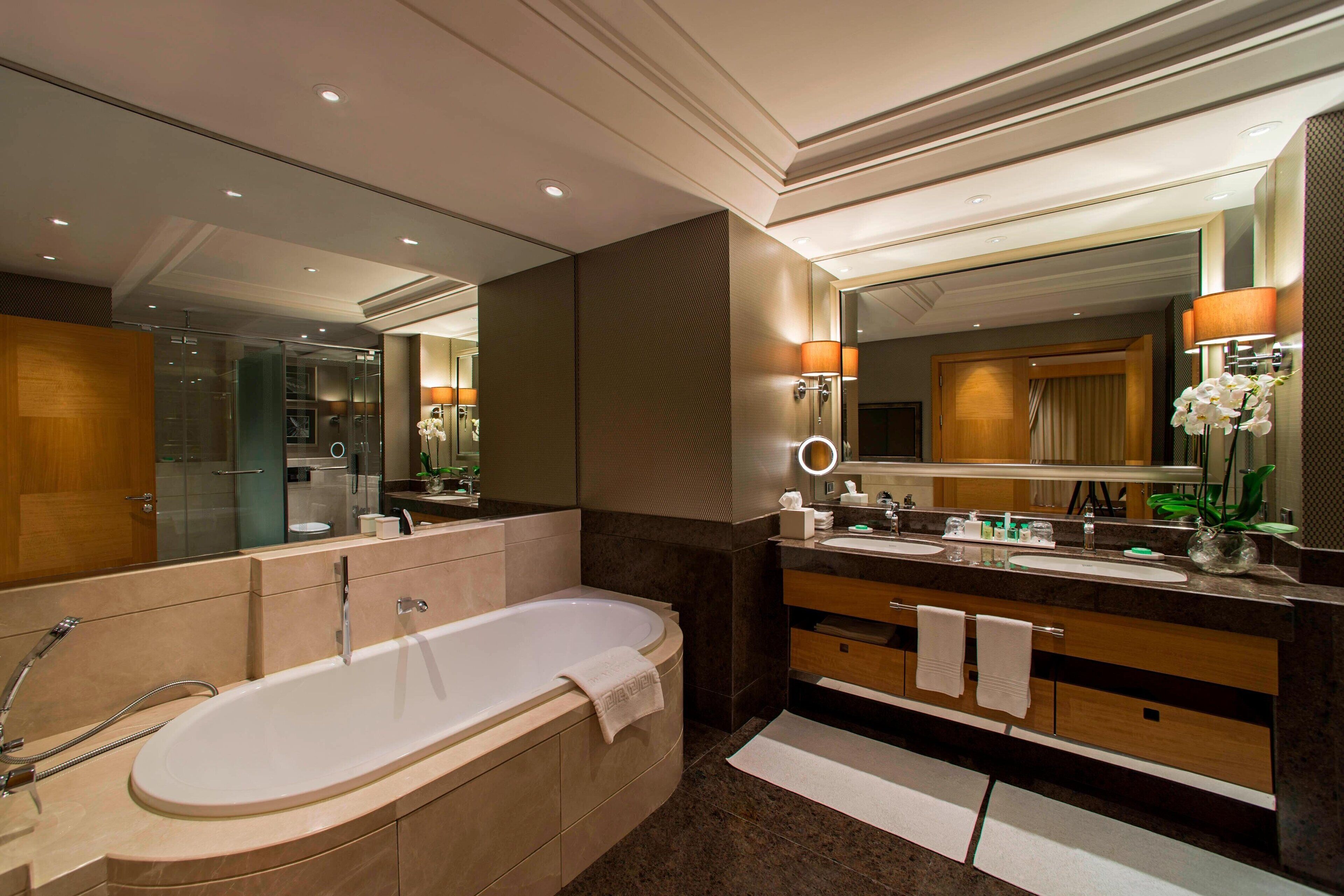 Un baño moderno con una bañera grande, un tocador con espejo y un lavamanos.