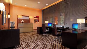 A hotel reception area with a reception desk, two computer monitors, a telephone, and a decorative statue.