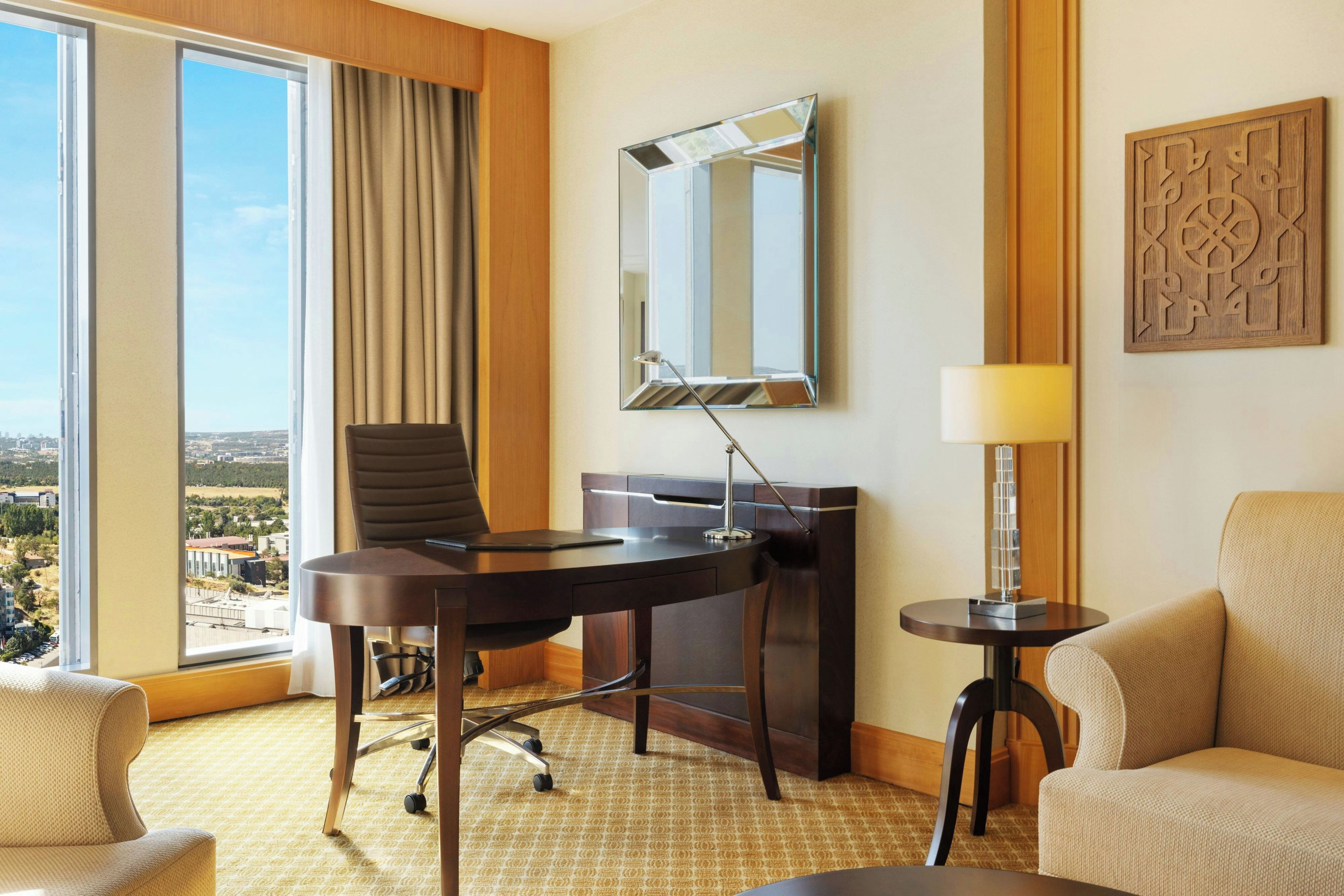 Habitación de hotel con escritorio, silla y vistas a la ciudad.