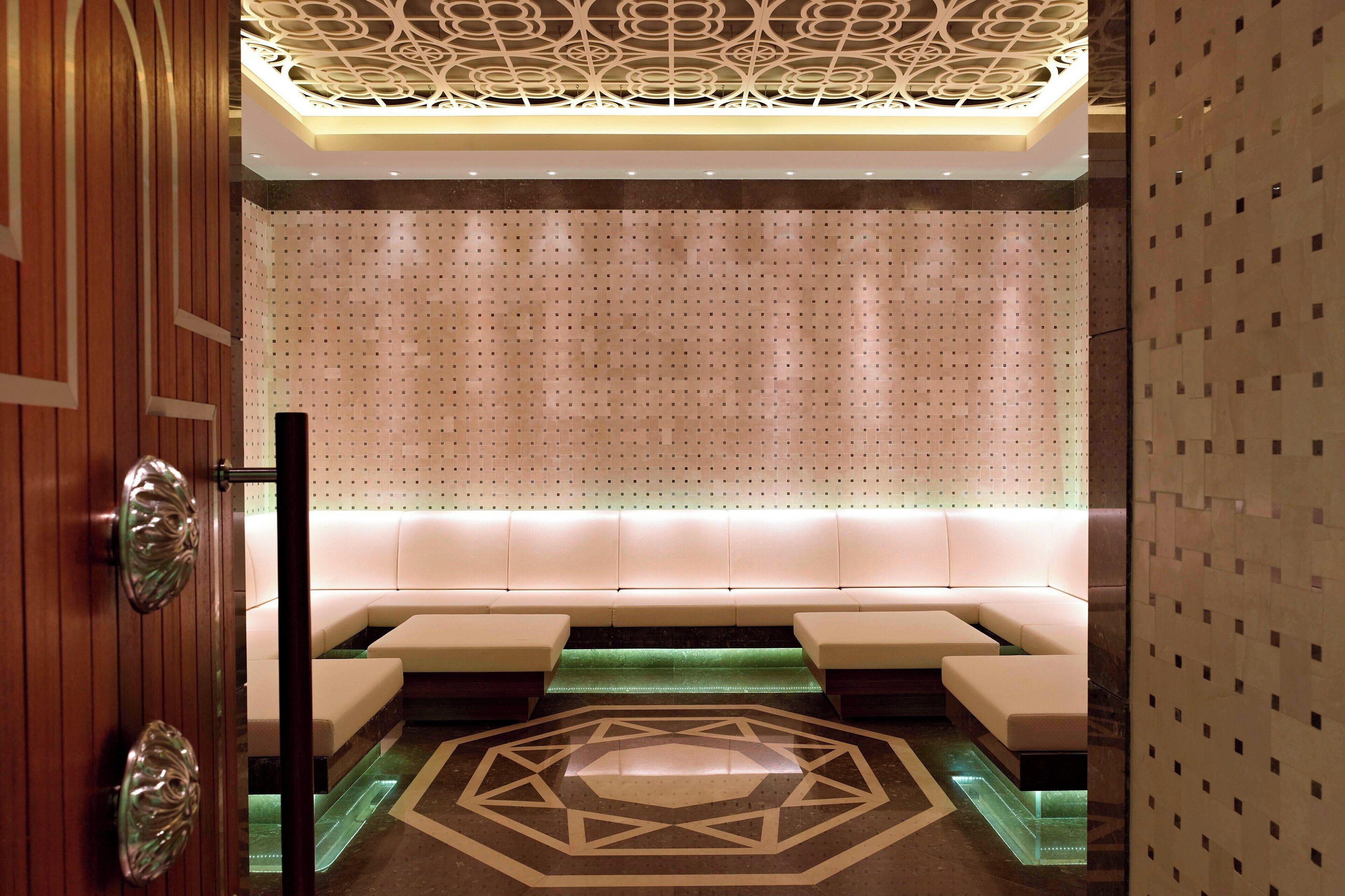A modern interior with a patterned wall, a seating area with cushions, and a geometric floor design.