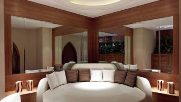 A modern bedroom with a large round bed, wooden paneling, and a large mirror.