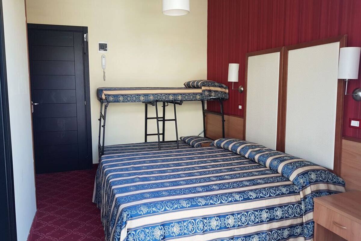 A room with a bunk bed, a desk, and a chair.