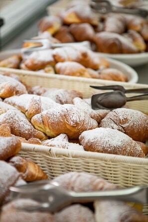 A variety of pastries, including croissants and other baked goods, displayed in baskets and on plates. - Hotel Promenade Universale (Cesenatico)