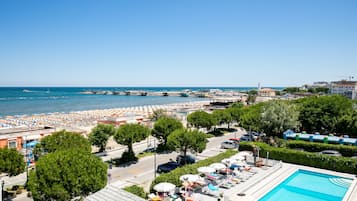 Un hotel sul lungomare con piscina, ombrelloni e vista mare.