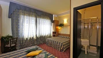 Camera d'albergo con due letti, una doccia, una sedia e una pianta.