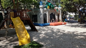 A playground with a slide, climbing structures, and a castle-like playhouse. - Hotel Promenade Universale (Cesenatico)