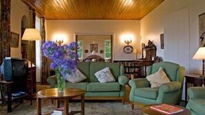 Un accogliente soggiorno con un divano verde, un tavolino in legno e un vaso con fiori viola.