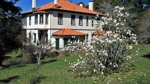 Una casa a due piani con tetto in tegole rosse, pareti bianche e persiane verdi.
