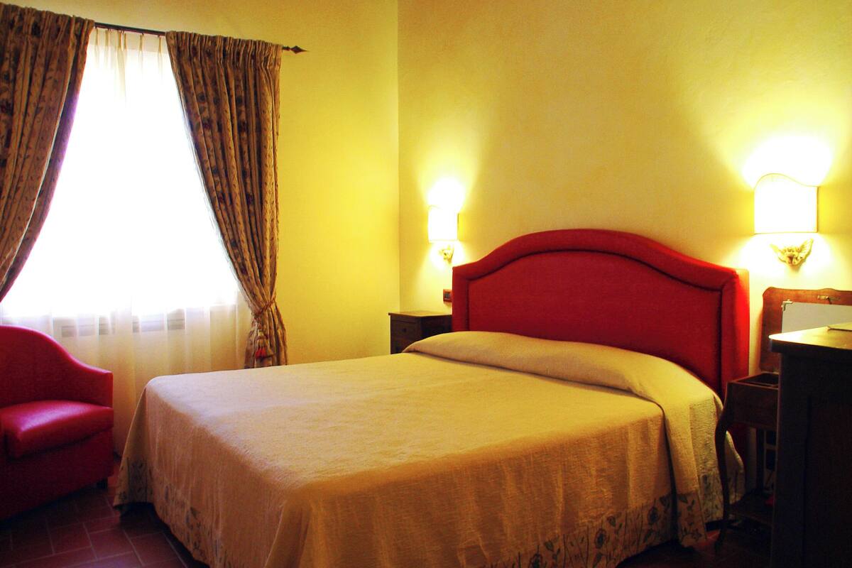Une chambre d’hôtel avec un lit, une chaise et deux lampes de chevet.