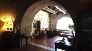 A cozy interior with a stone archway, a dining area with a table and chairs, and a view through a window.