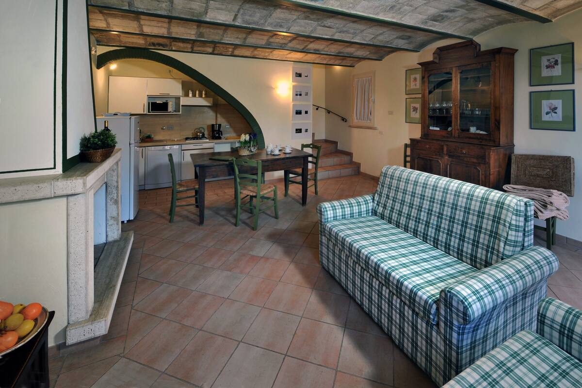 Un salon confortable avec un canapé, une table à manger avec des chaises, une cuisine équipée d’un four à micro-ondes et un escalier menant à l’étage.