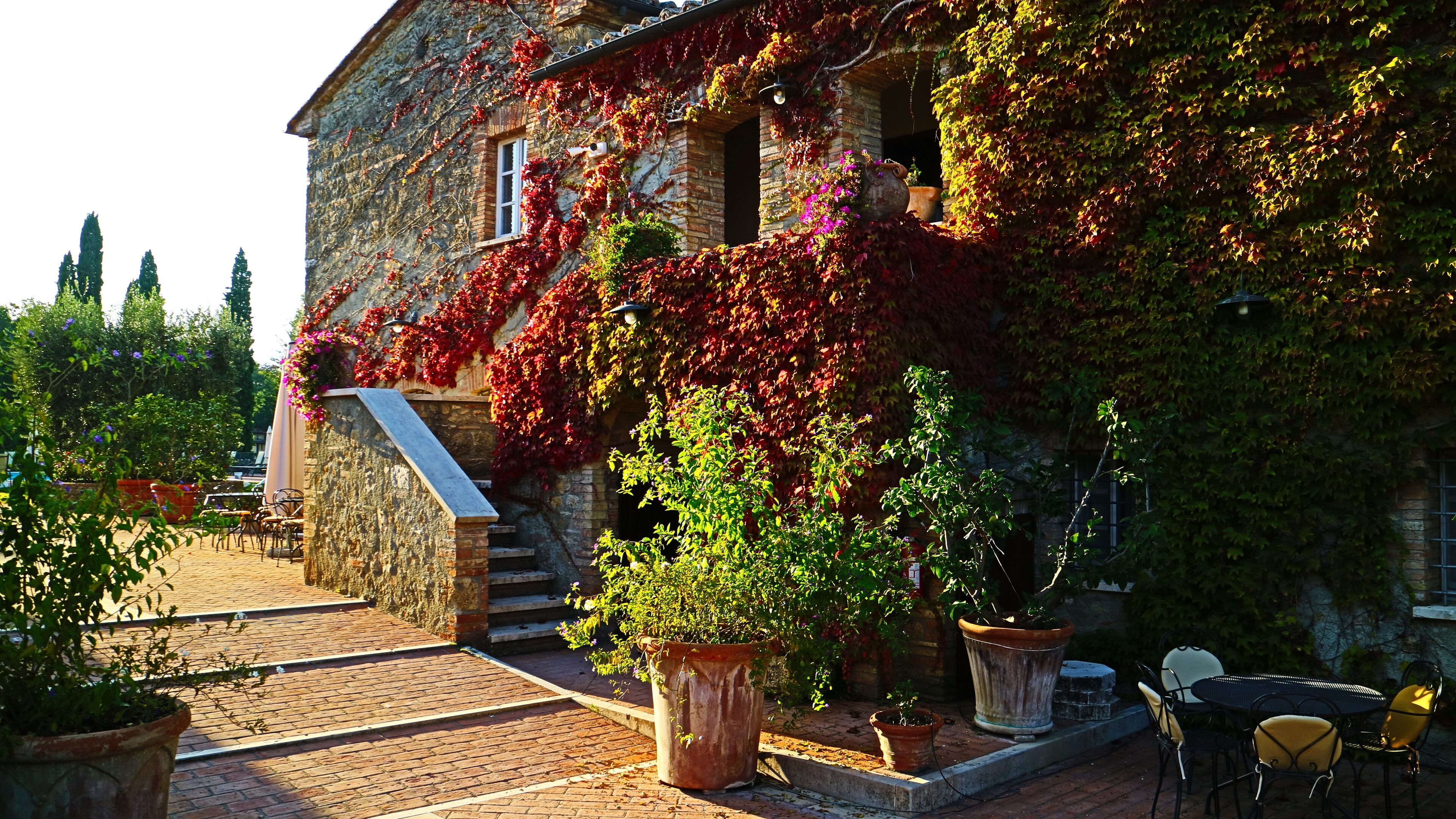 Ein Steinhaus mit Efeu bewachsenen Wänden, Außenbereich mit Sitzgelegenheiten und Pflanzgefäßen.