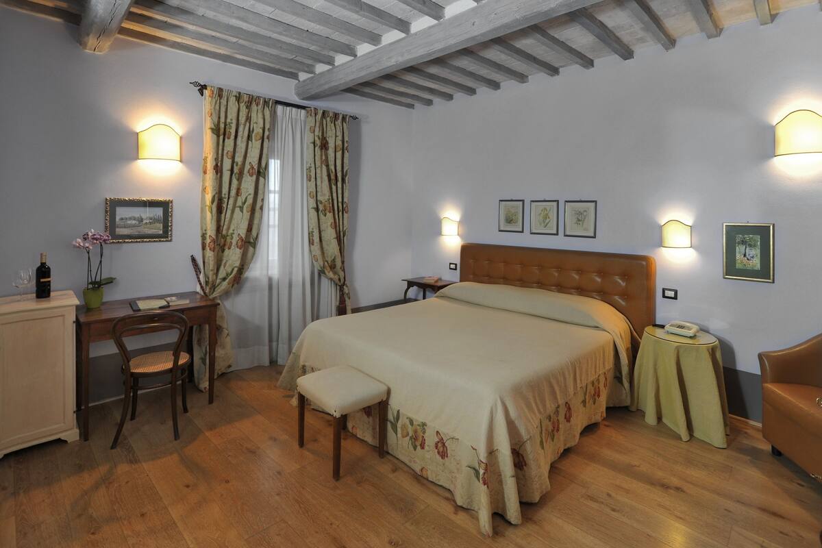 Une chambre à coucher avec un lit en bois, un bureau, une chaise, une petite table et un placard.