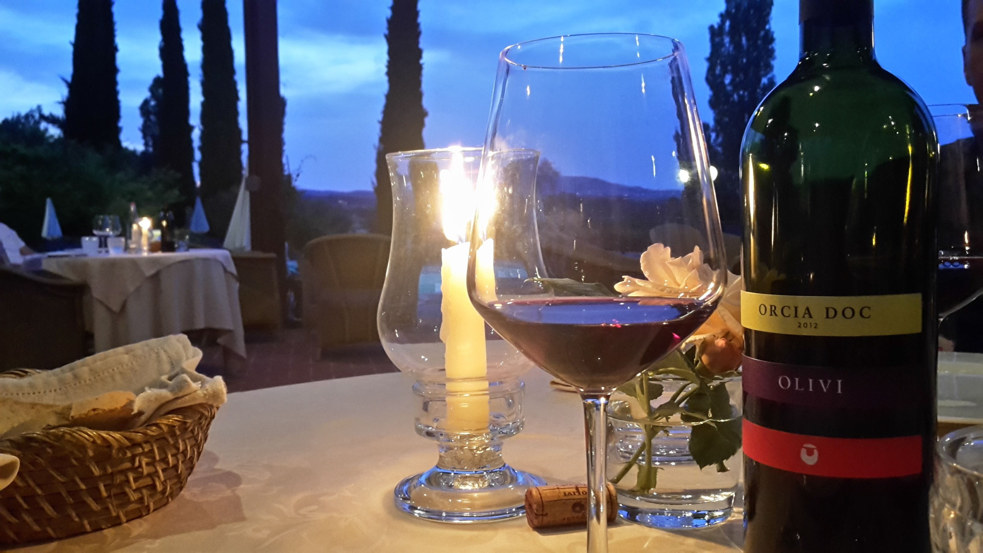 Une table dressée avec une bouteille de vin, des verres et une bougie.