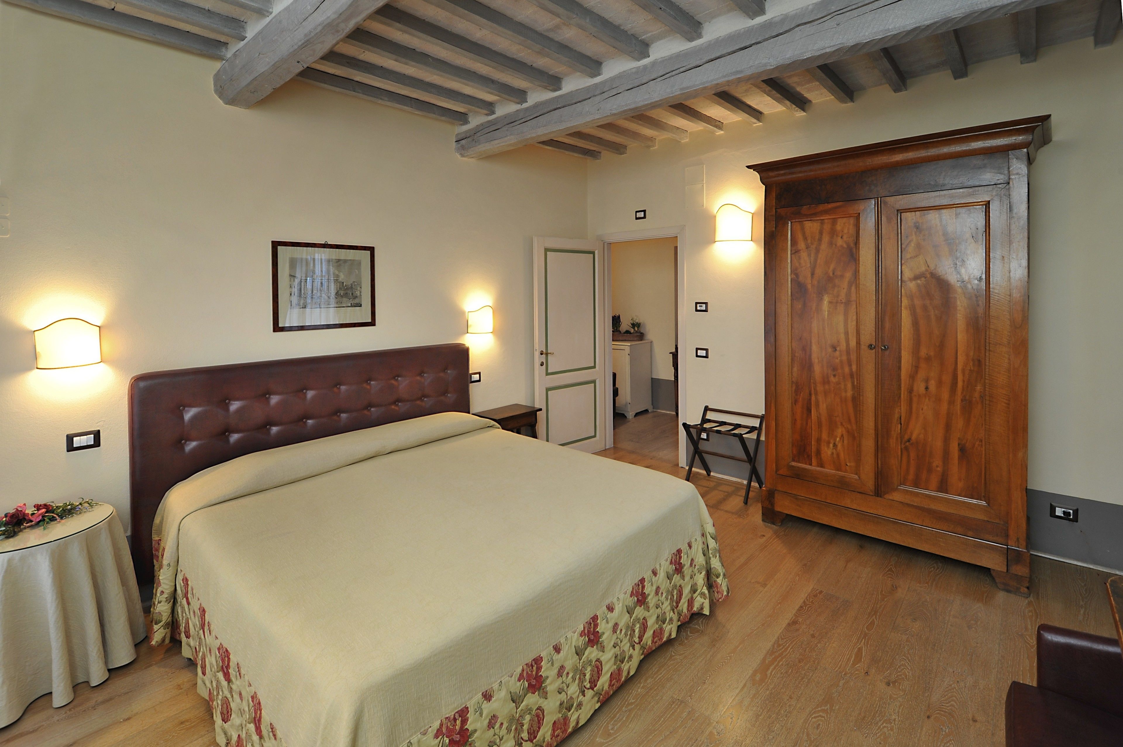 A bedroom with a large bed, wooden wardrobe, and two bedside tables.