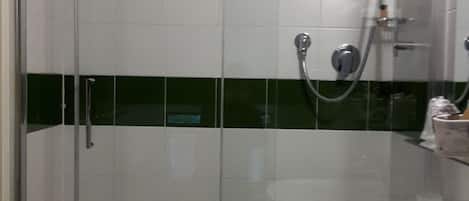 A bathroom with a glass-enclosed shower, a white sink, and a green stripe on the wall.