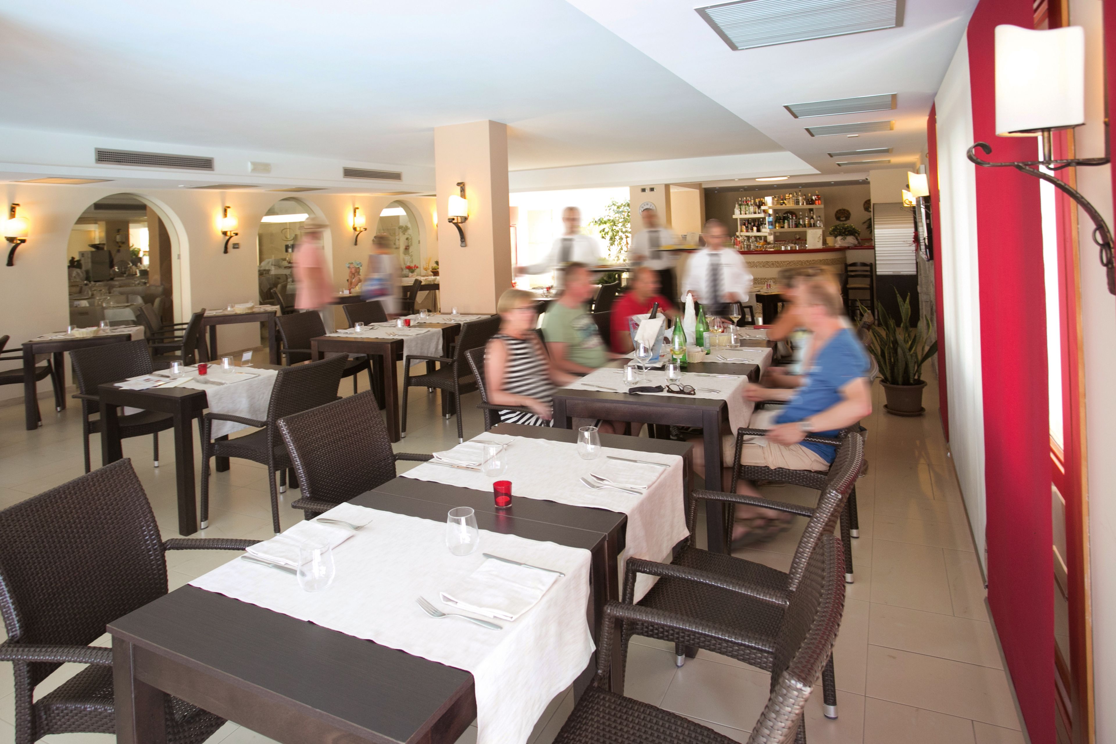 A restaurant with multiple tables and chairs, some occupied by diners.