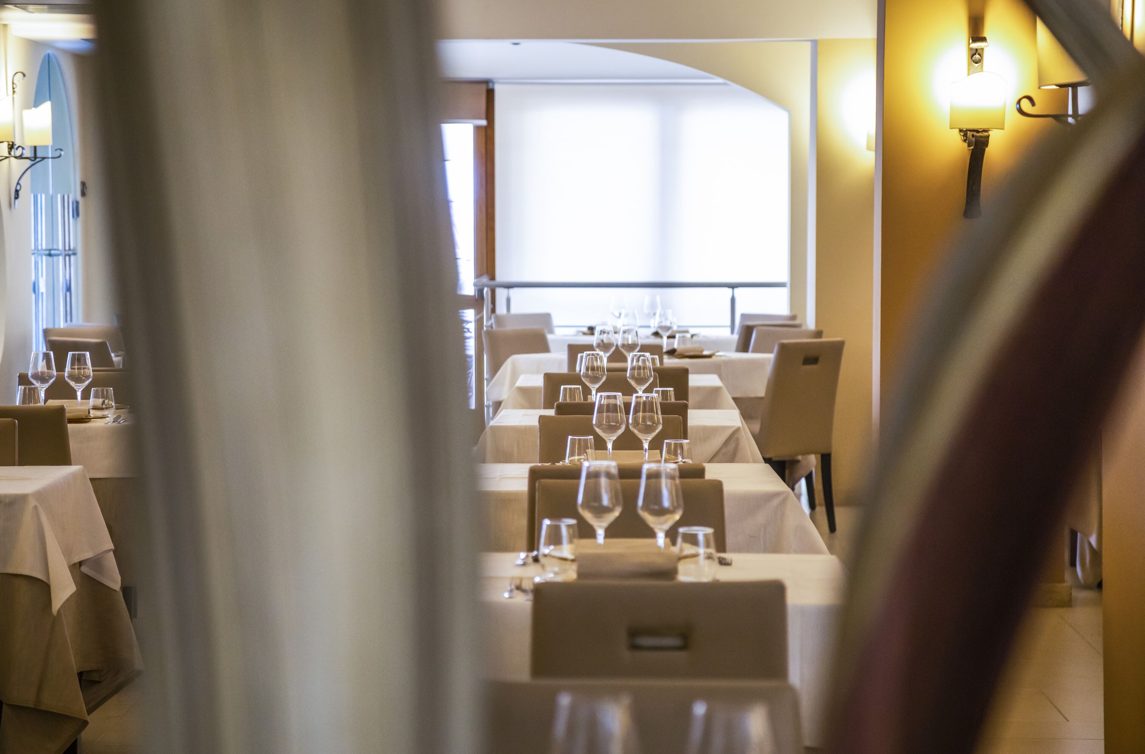 Un restaurante con mesas dispuestas para comer, un ventanal grande y una lámpara fijada en la pared.