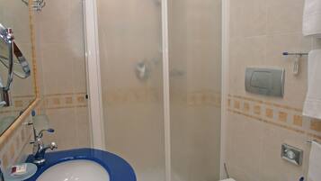 A bathroom with a blue sink, white toilet, and a glass-enclosed shower.