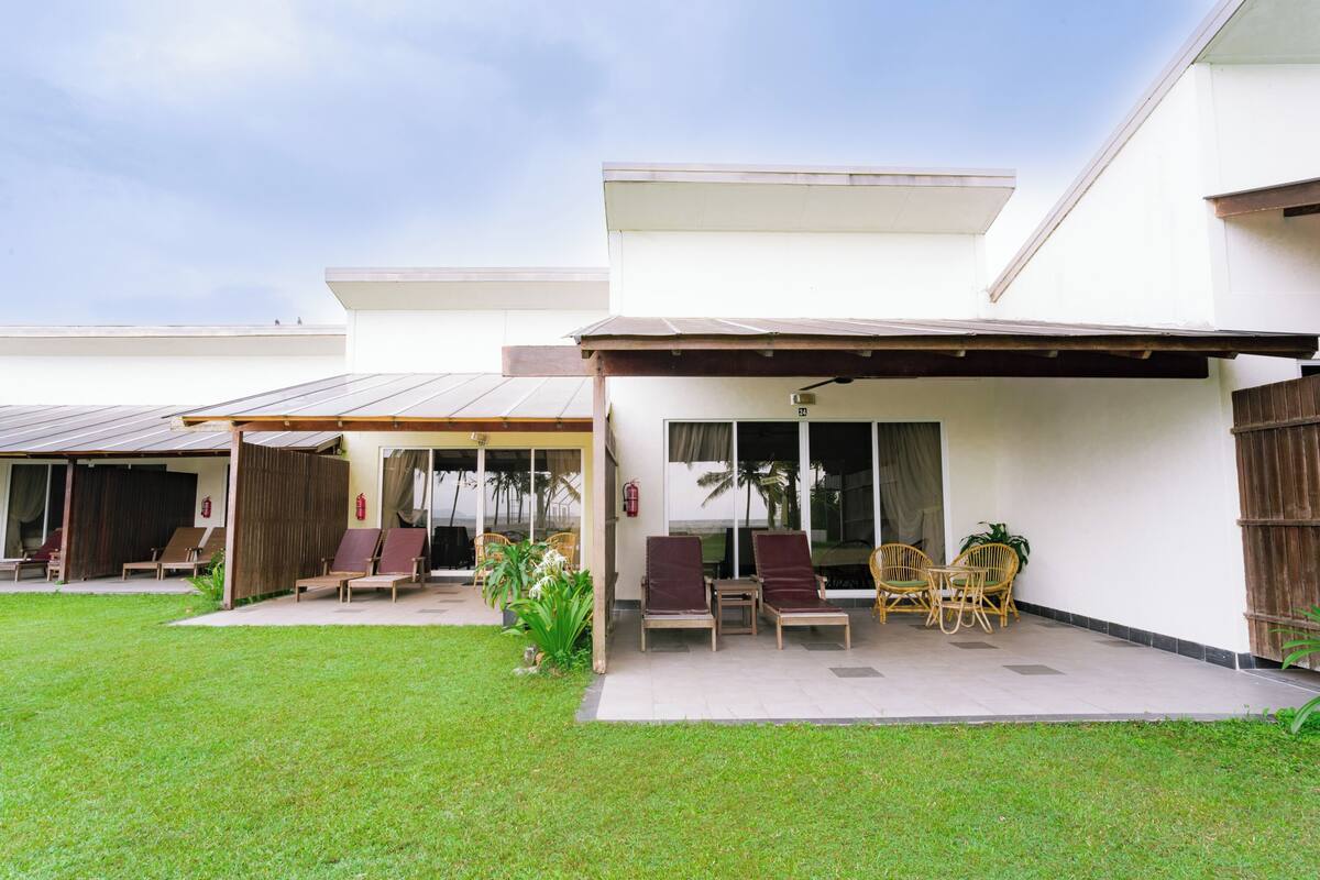 A modern building with a covered patio area featuring lounge chairs and a small table.