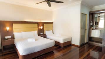 A hotel room with two beds, a ceiling fan, bedside lamps, a minibar, and a mirror.