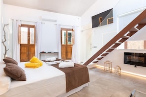 Una habitación de hotel moderna con una cama, un armario de madera, una escalera y un televisor montado en la pared.