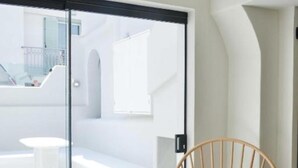 A modern room with a wooden chair, a white sofa, and a glass door leading to an outdoor area.