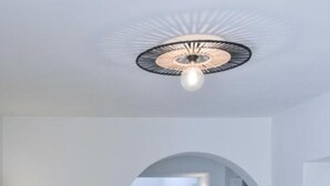 A modern interior with a dining area featuring a table and chairs, a unique ceiling light fixture, and a staircase leading to another level.