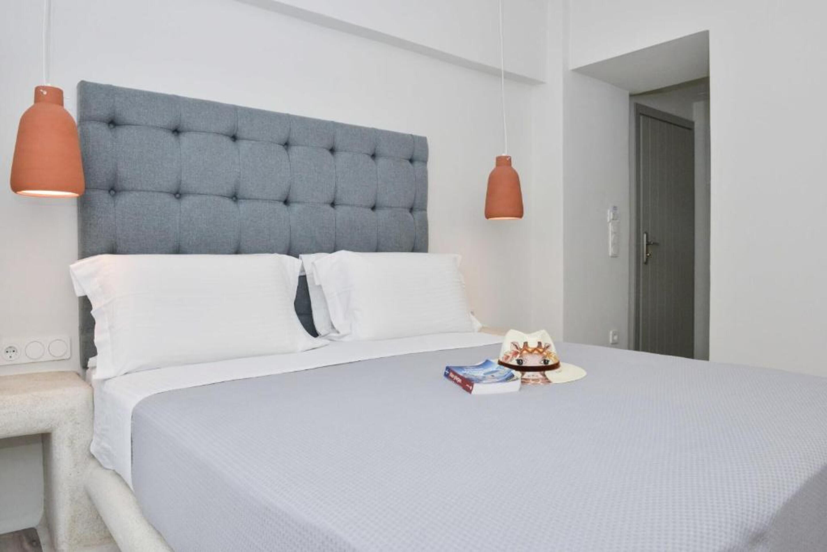 A neatly made bed with a grey tufted headboard, white pillows, and a small decorative item on the bed.