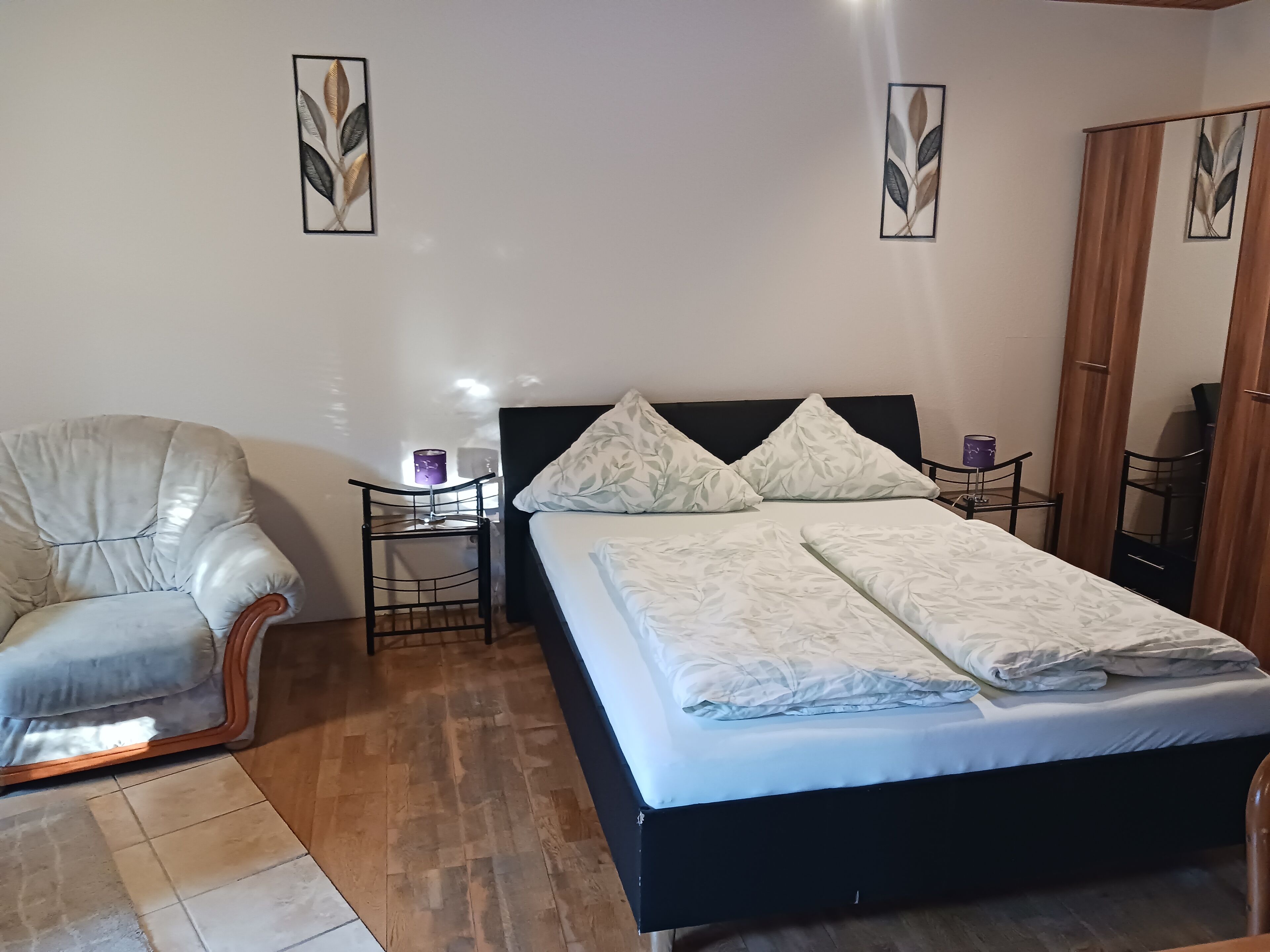Une chambre à coucher avec un lit, une chaise, une table de chevet et une armoire.