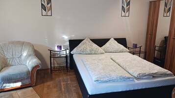 Une chambre à coucher avec un lit, une chaise, une table de chevet et une armoire.
