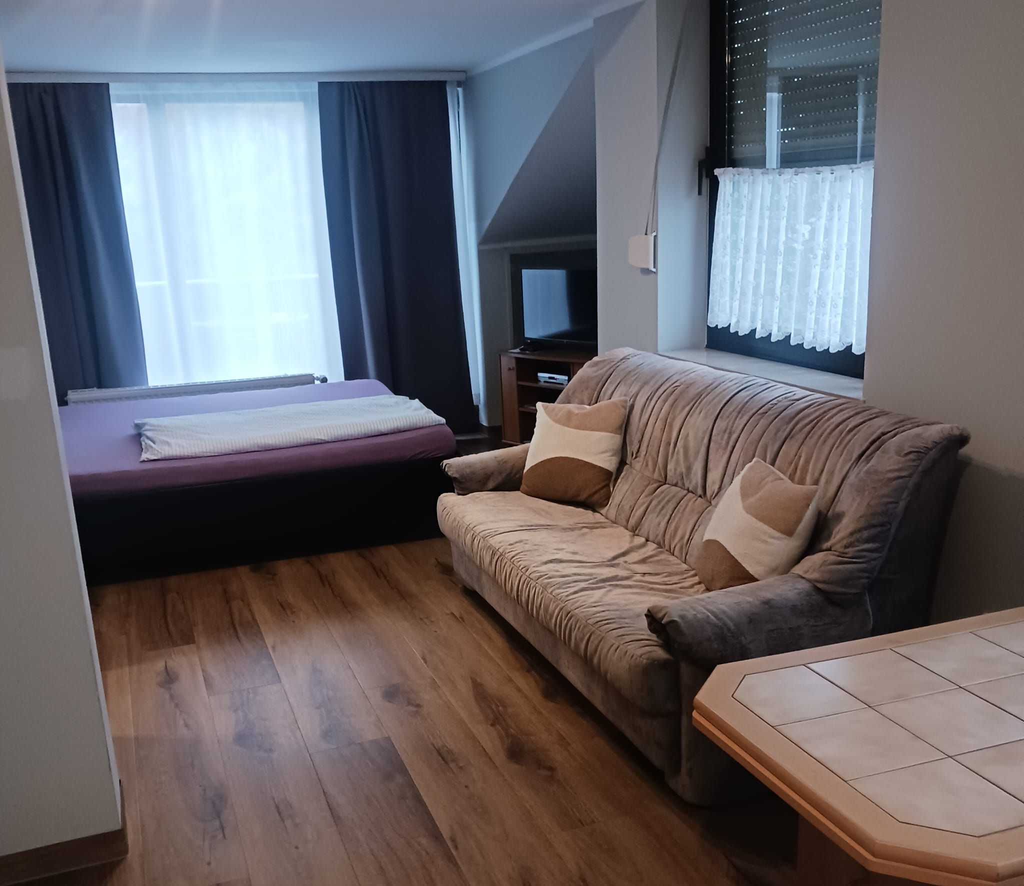 Uma sala de estar moderna com um sofá, uma mesinha e uma cama.