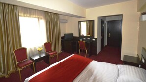 A hotel room with a bed, a desk, two chairs, a mirror, and a door. - Ancor Hotel (Voluntari)
